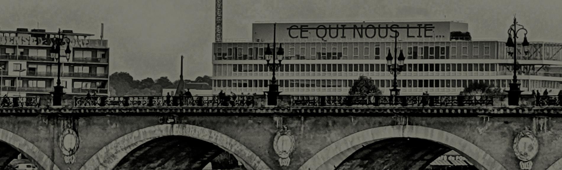 Image of a bridge with 'Ce qui nous lie' appearing on a building in the background