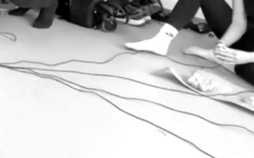 People are sitting on the ground, behind intertwined wires. We only see the bottom half of the people.
