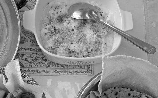 A metal spoon in a bowls of food. There are other bowls around it.