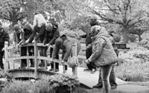 A group of people looking at a pond from a bridge